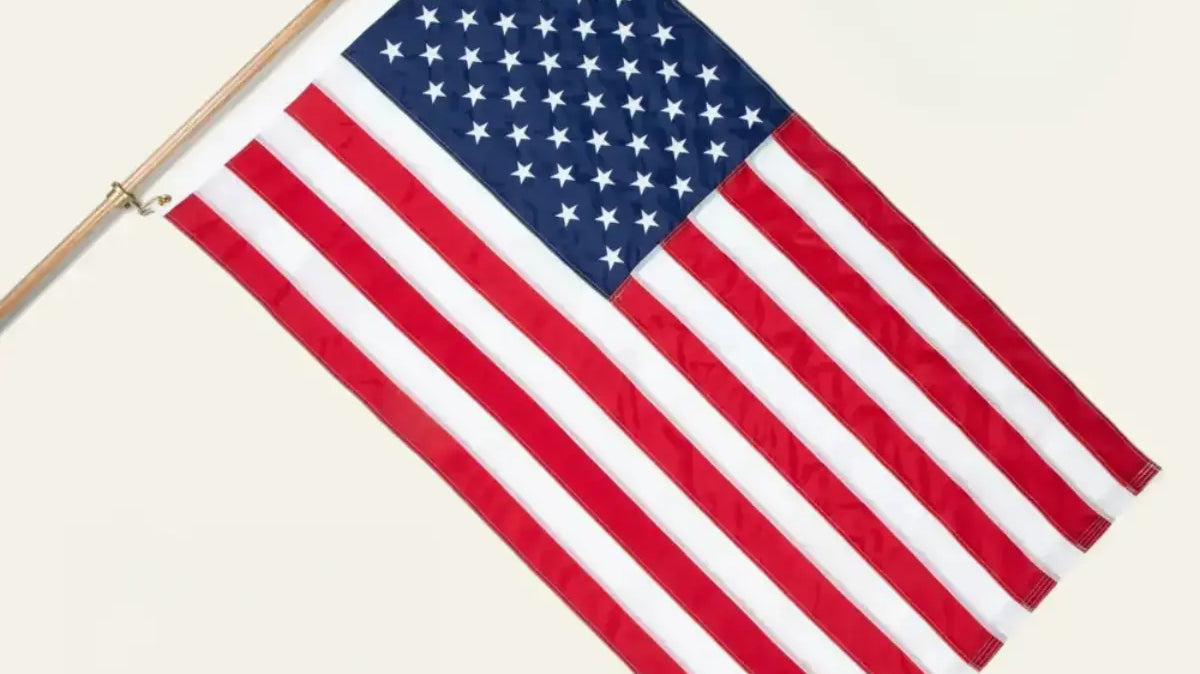 American flag mounted on a wooden pole against a plain white background.