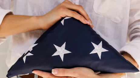 American flag carefully folded and held in a woman's hands, symbolizing respect and patriotism