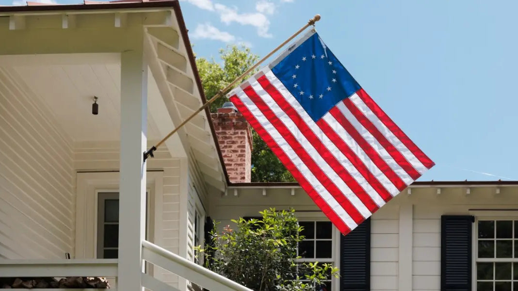 American flag placement for businesses and homes featuring a Betsy Ross flag mounted on a white house porch.