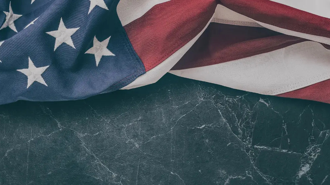 Common U.S. flag draped on dark marble surface showing stars and stripes in close-up detail.