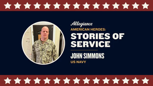 John Simmons, wearing a U.S. Navy uniform, stands in front of a doorway with a serious expression