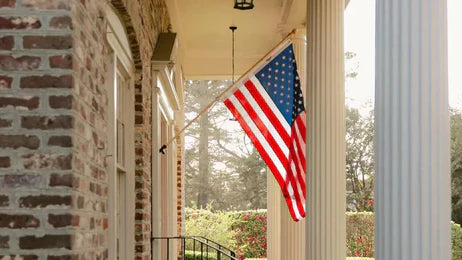All-weather American flag mounted on a brick colonial-style porch, waving between elegant white columns