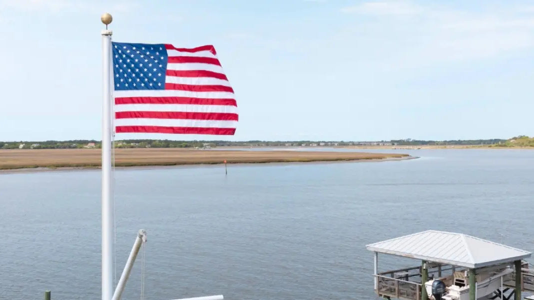 Custom boat flag wave from a white pole on a motorboat deck under a clear blue sky