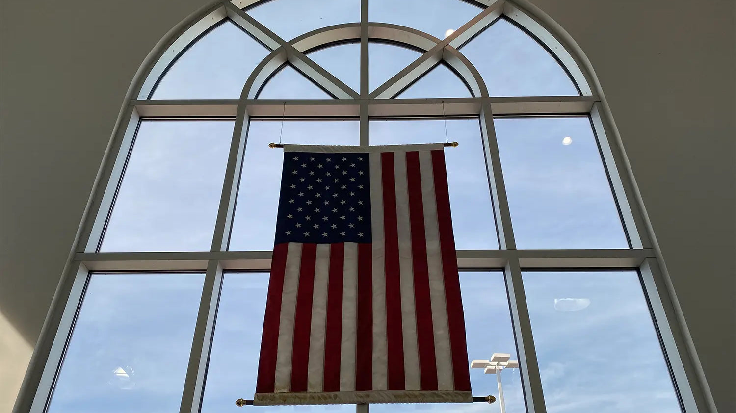United States flag hanging vertically in the center of a large window.