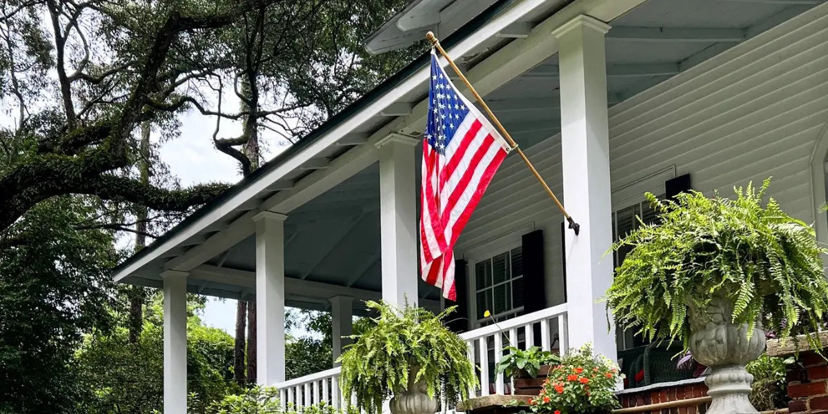 American flag kit displayed on a white porch with hanging ferns and lush trees in the background.