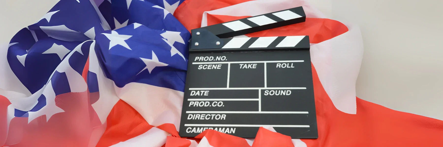 American flag draped beneath a film clapperboard symbolizing patriotic moments in American cinema.