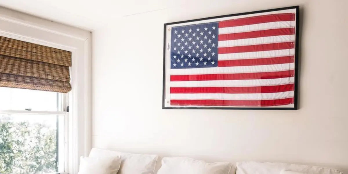 American flag displayed in a black frame above a white couch against a bright cream living room wall