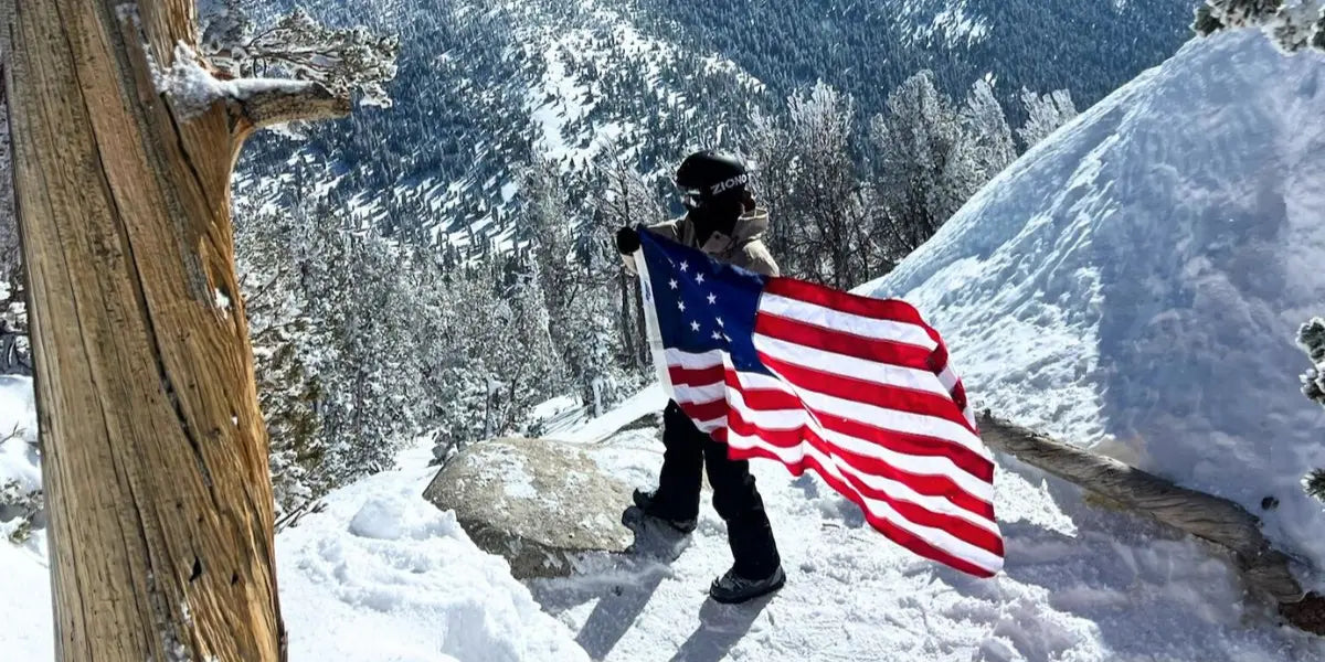 American flag etiquette followed as a hiker holds the flag respectfully on a snowy mountain trail.