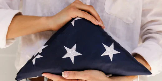 American flag carefully folded and held in a woman's hands, symbolizing respect and patriotism