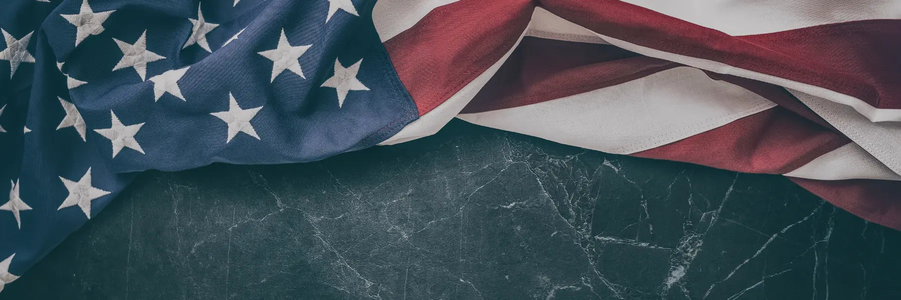 Common U.S. flag draped on dark marble surface showing stars and stripes in close-up detail.
