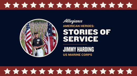 Jimmy Harding stands among numerous American flags in a field, wearing a hat & holding a document